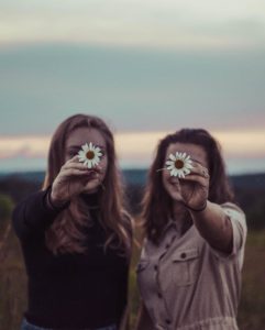 Two young women holding daisies